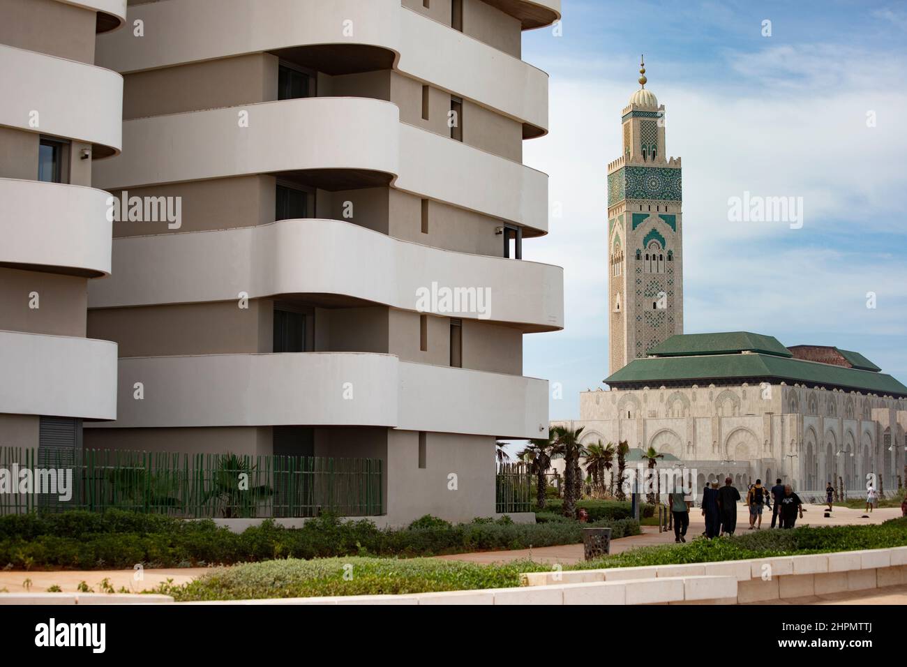 La Mezquita Hassan II está junto a edificios de apartamentos contemporáneos en la costa de Casablanca, Marruecos. Foto de stock