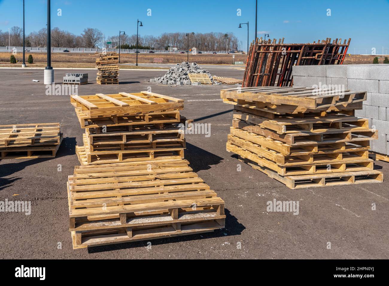 Tiro horizontal de pilas de palets de madera y otros suministros en un sitio de construcción industrial. Foto de stock