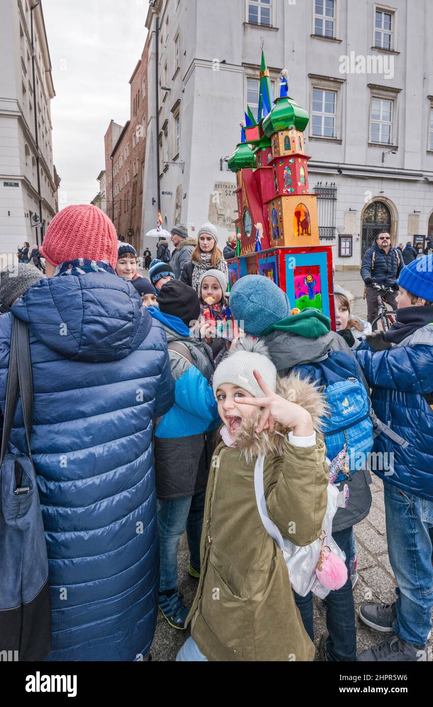 Escolares que llevan la escena de la natividad de Kraków Szopka, realizada por ellos en la escuela, para su exhibición durante el concurso anual de diciembre, evento incluido en la Lista del Patrimonio Cultural de la UNESCO, en la Plaza del Mercado Principal, Kraków, Polonia Foto de stock