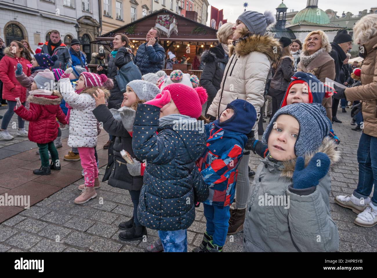 Jóvenes escolares, profesor, mirando las escenas de la natividad de Kraków Szopka, exhibidas durante el concurso anual en diciembre, en el monumento Adam Mickiewicz, Plaza del Mercado Principal, Kraków, Polonia Foto de stock