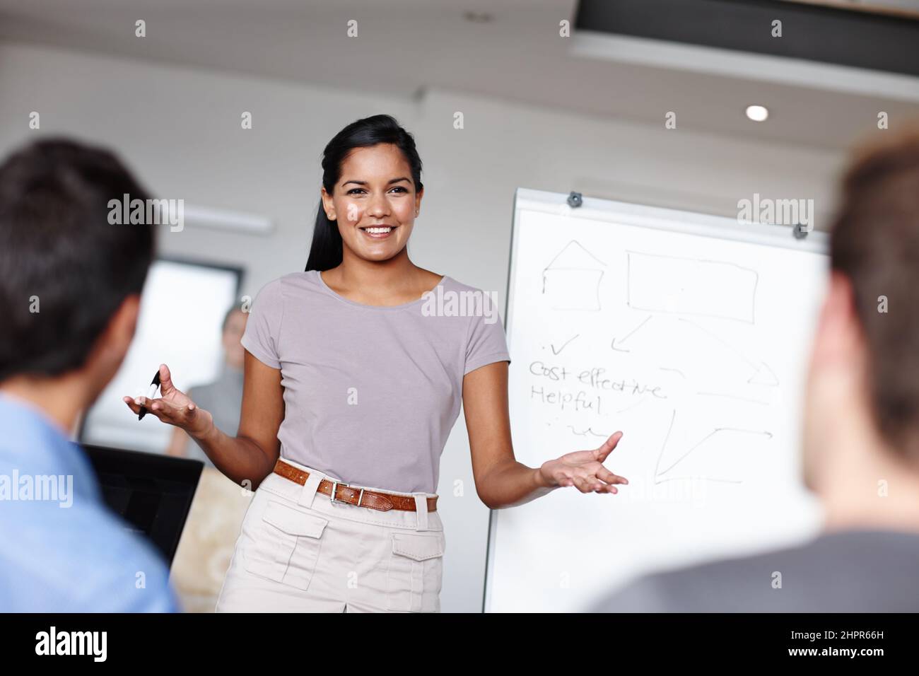 Factible es su especialidad. Una joven empresaria que facilita una reunión económica en la sala de juntas. Foto de stock