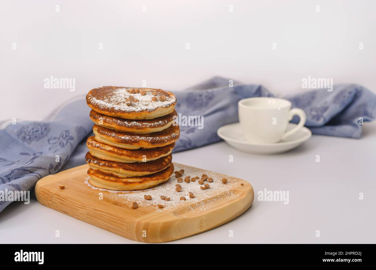 el desayuno consiste en una pila de tortitas sobre un plato de madera sobre un fondo blanco. Foto de stock