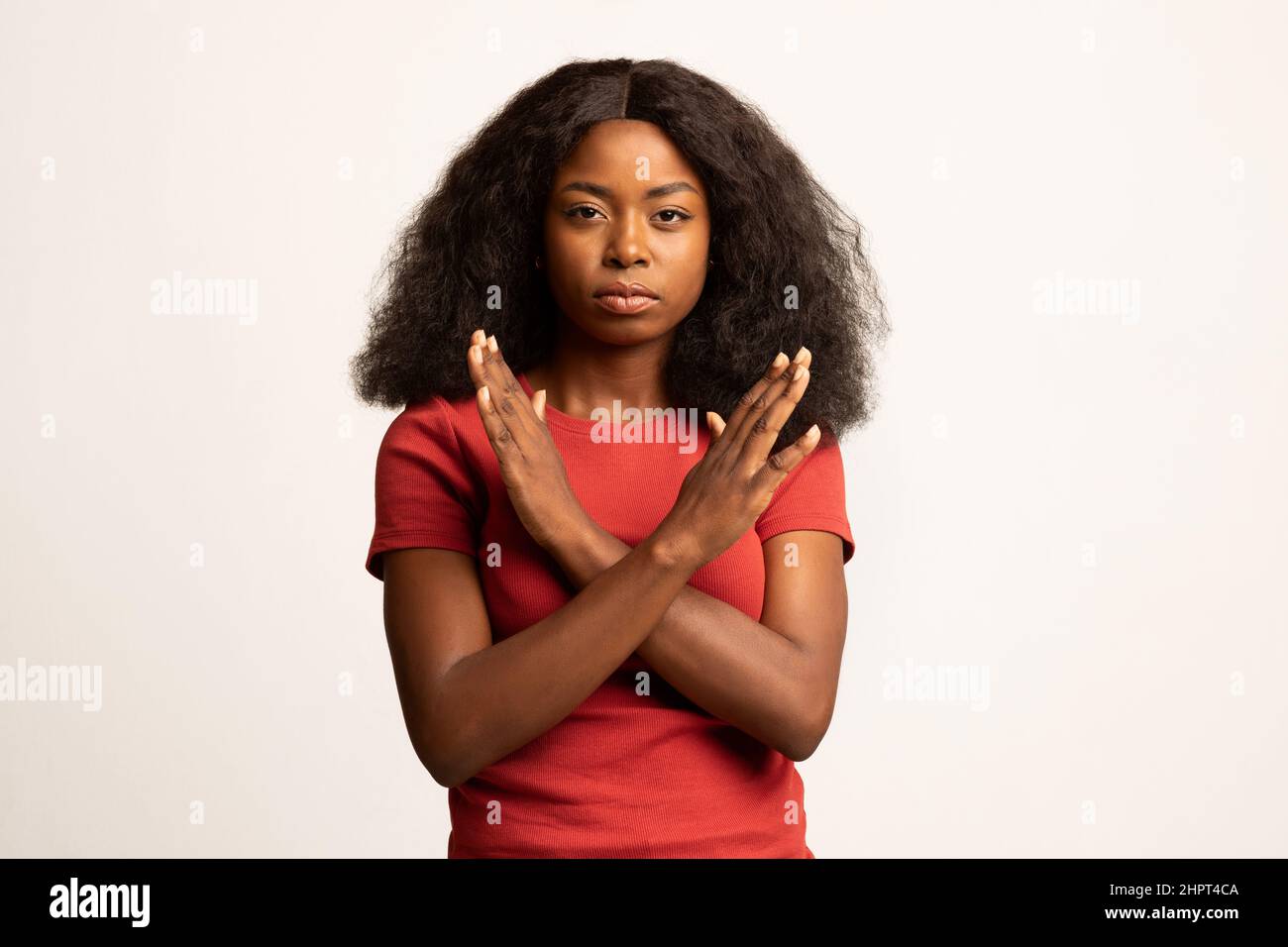 Retrato de una joven mujer negra mostrando un gesto de detención con las manos cruzadas Foto de stock