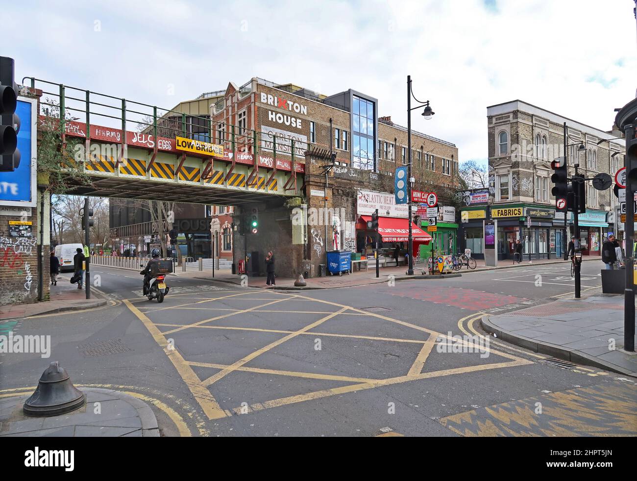 Brixton, Londres, Reino Unido. El concurrido cruce de Coldharbor Lane y Atlantic Road, que muestra el puente ferroviario, las tiendas y el nuevo edificio de Brixton House. Foto de stock