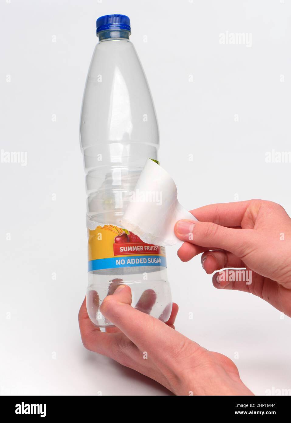 Eliminación de una etiqueta de de una botella de plástico de bebidas de calabaza de un solo uso para reciclaje fotografiada sobre un blanco Fotografía de stock - Alamy