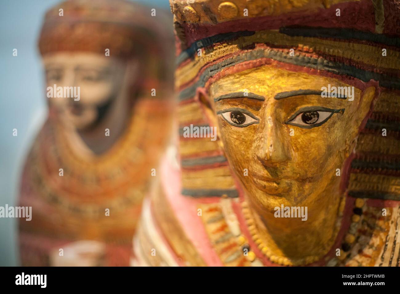 Esculturas de la cubierta de la mami egipcia en el Museo Británico: La cara de una mujer con una escultura de mle en el fondo forma parte de la exposición sobre artefactos egipcios antiguos en el Museo Británico. Foto de stock
