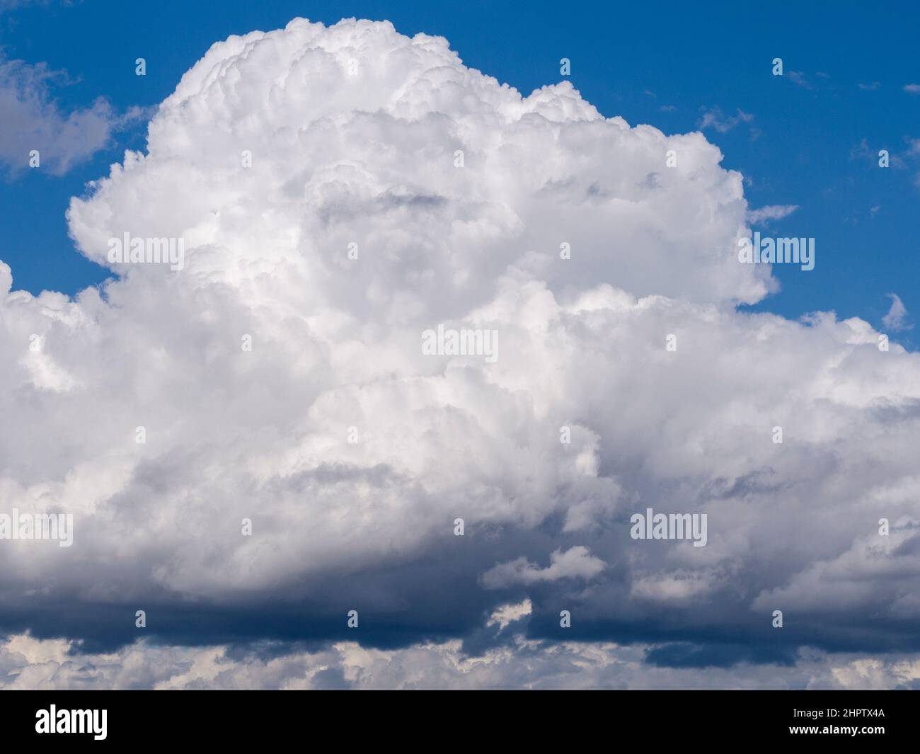 Construyendo la Nube de Tormenta: Un edificio de nube de tormenta de lage cumulus sobre el río Ottawa. Un cielo azul brillante por encima, gris oscuro por debajo. Foto de stock