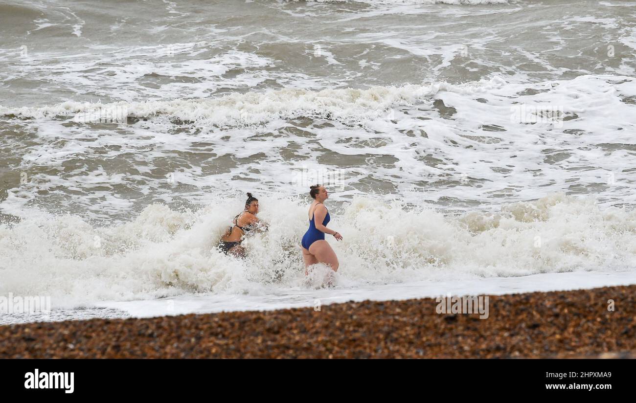 Brighton UK 24th Febrero 2022 - Un par de nadadores temprano por la mañana se atreve con el clima húmedo y ventoso en Hove después de las recientes tormentas que han causado inundaciones y daños en todo el país : Credit Simon Dack / Alamy Live News Foto de stock