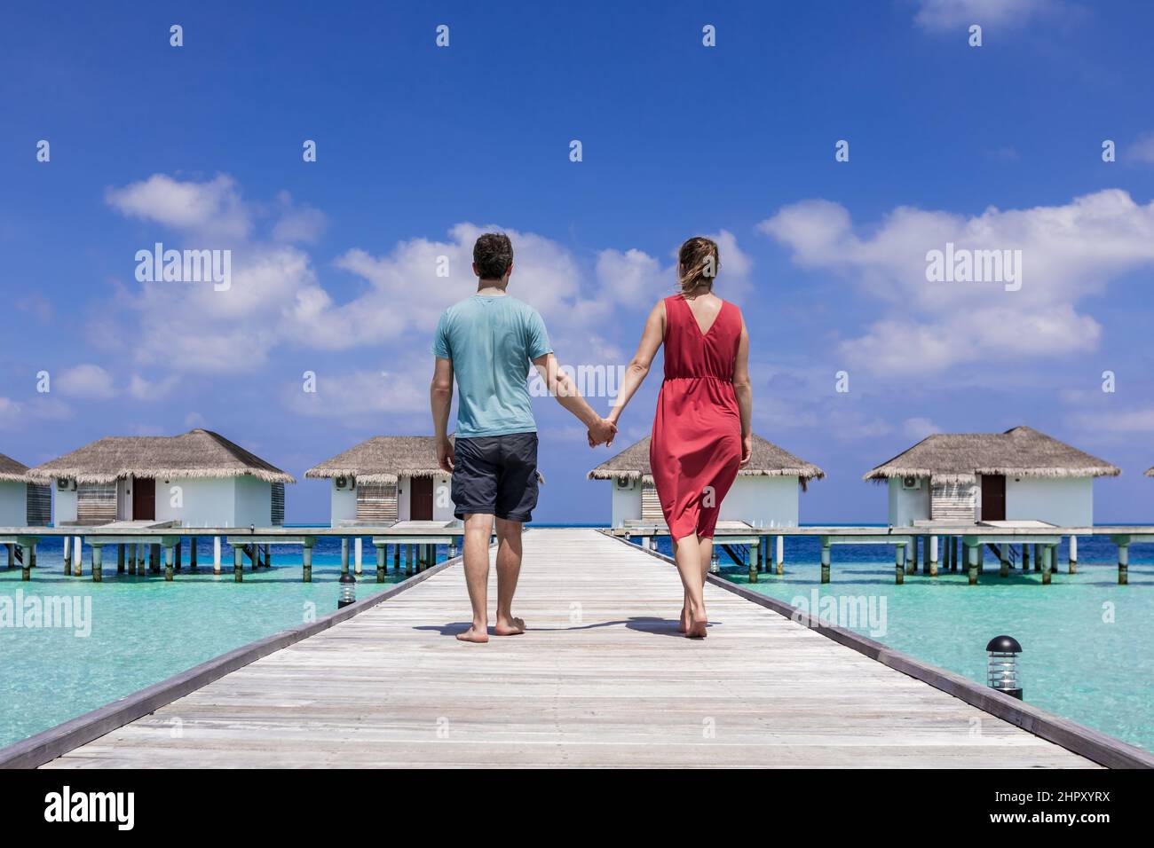 Pareja pasando vacaciones románticas en la playa en un complejo de lujo en Maldivas con villas sobre el agua, aguas turquesas y cielo azul. Paraíso ato Foto de stock