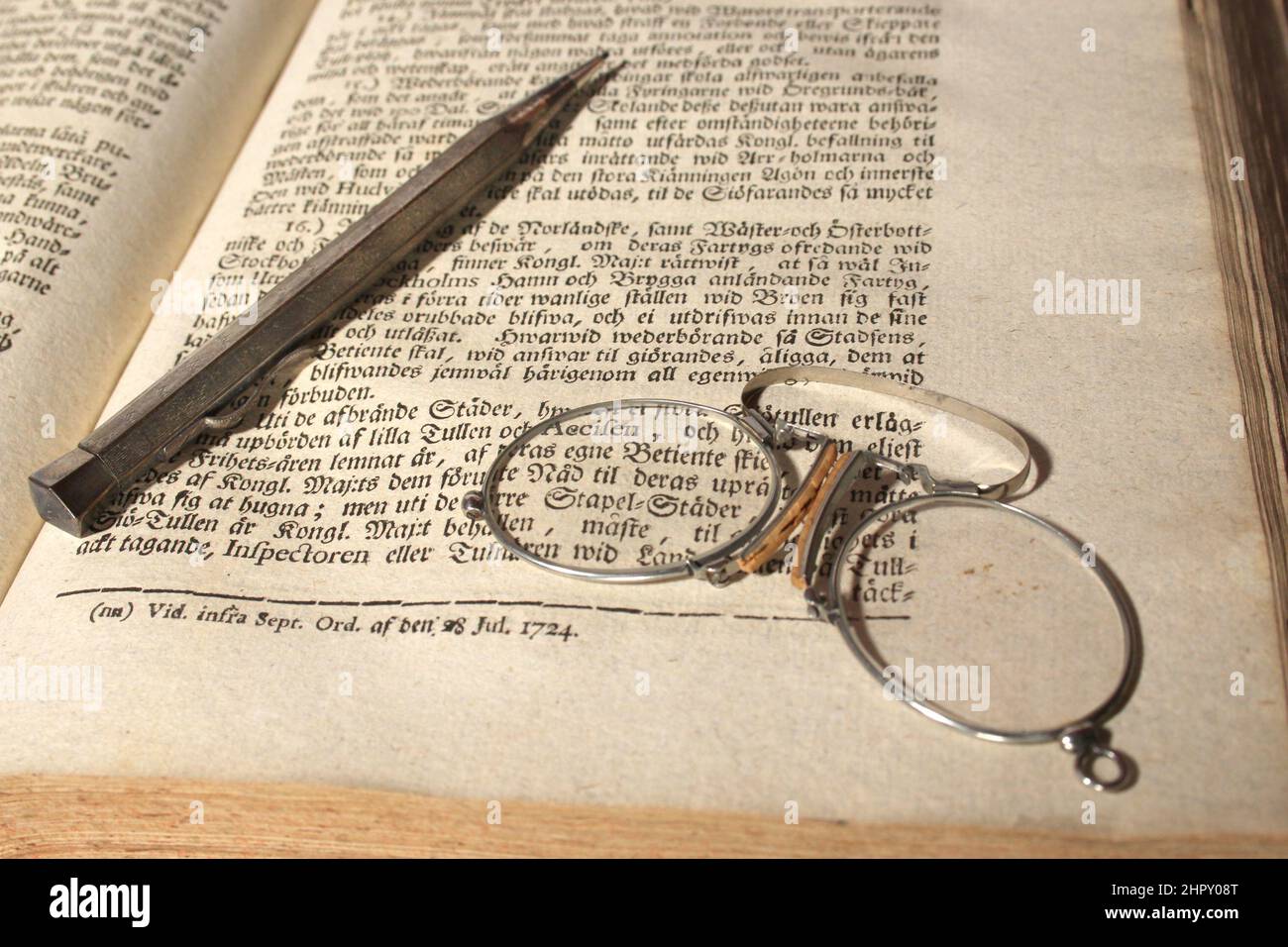 Las gafas y el lápiz mecánico del erudito de finales del siglo 19th se dejan tumbados en un libro de 1724 Foto de stock