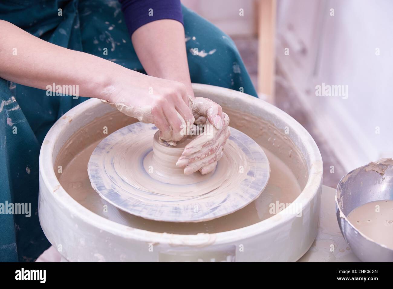 las manos de un ceramista hacen platos en la rueda de un alfarero Foto de stock