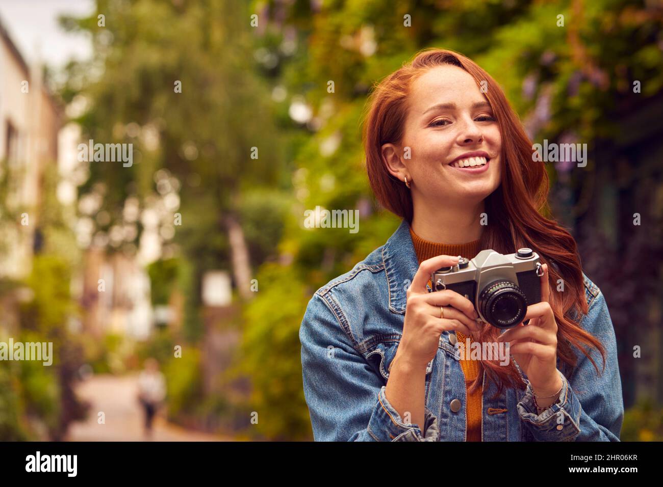 Mujer joven en la ciudad Tomando foto con cámara digital para publicar en los medios sociales Foto de stock