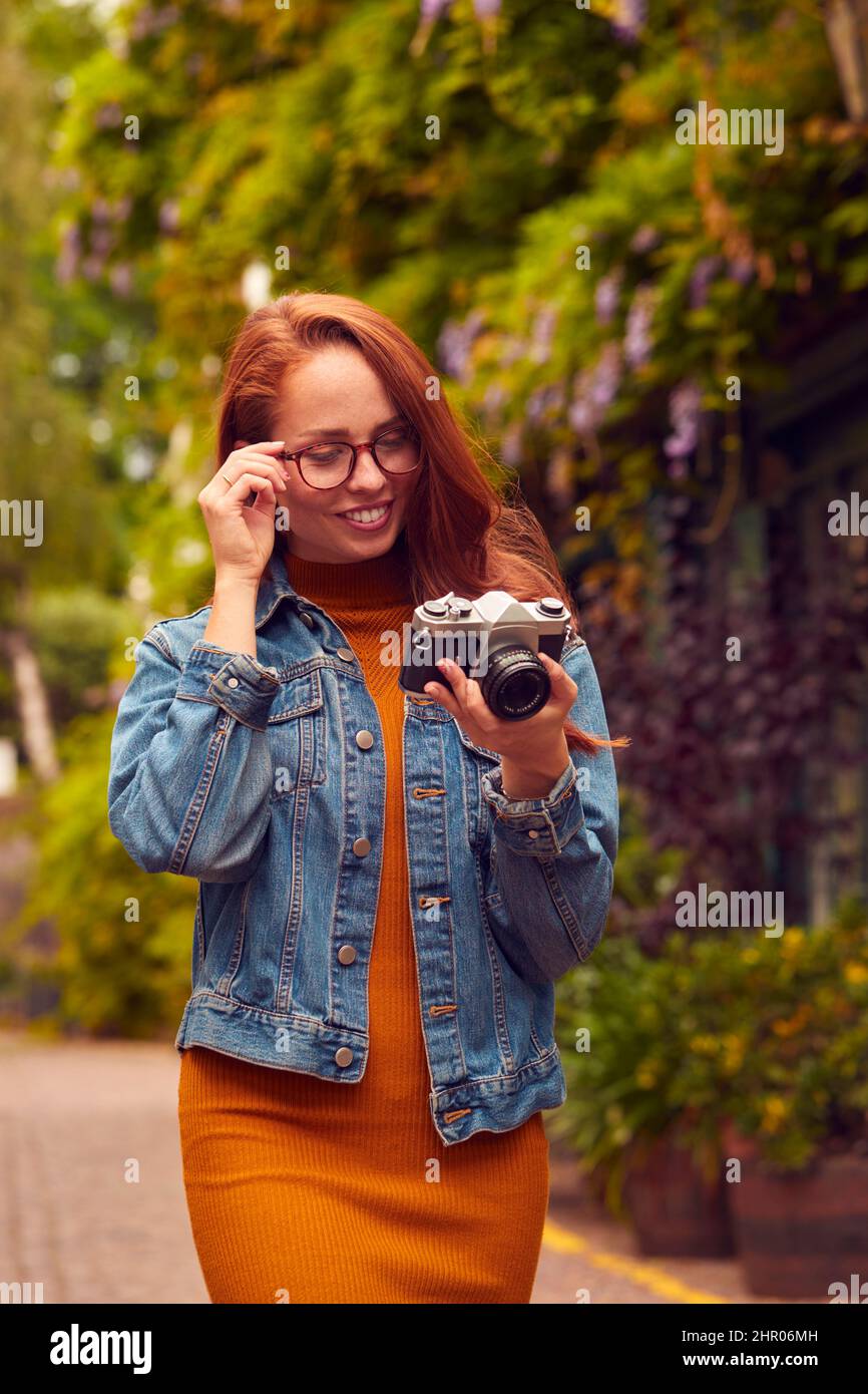 Mujer joven en la ciudad Tomando foto con cámara digital para publicar en los medios sociales Foto de stock