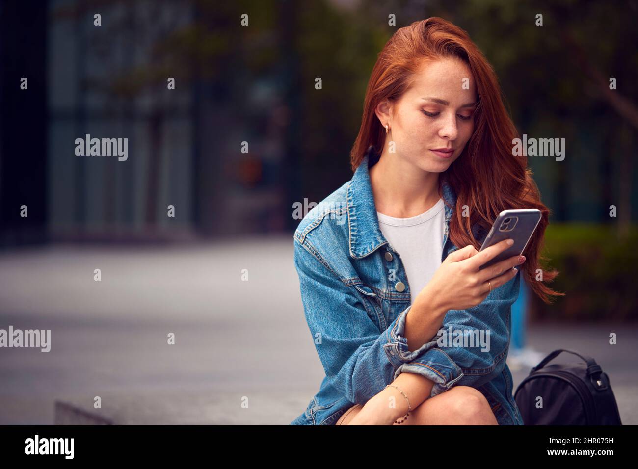 Mujer Vlogger o Influenciador Social en la Ciudad usando el teléfono móvil en la calle para publicar en las redes sociales Foto de stock