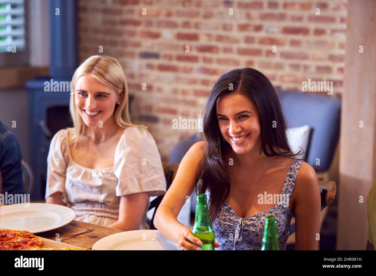 Dos amigas disfrutando de la comida Takeaway en casa junto con sus amigos Foto de stock