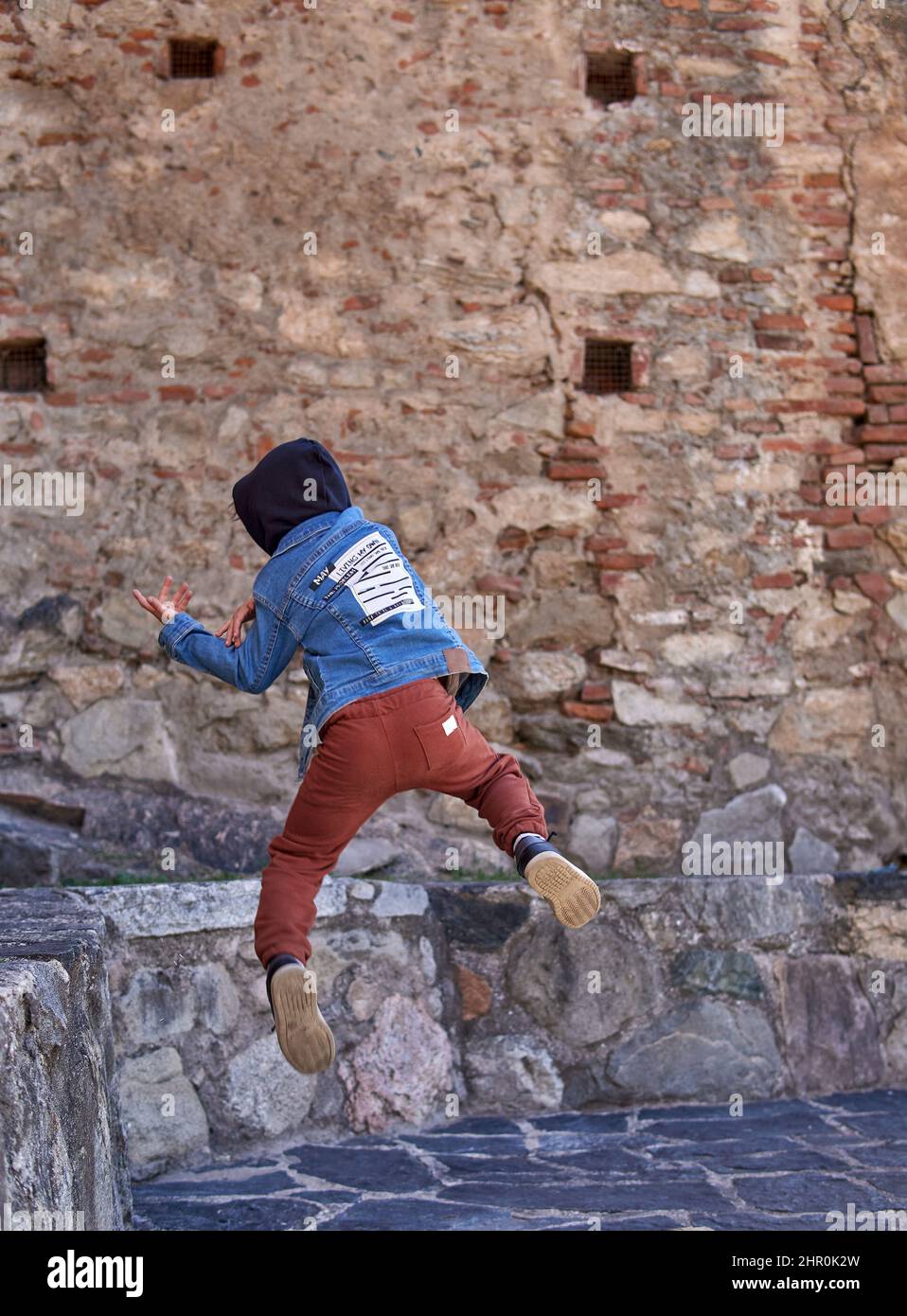 niño niño en la capucha practicando pirouettes en la vieja ciudad solamente. concepto de una vida parkour de los cabritos. vertical Foto de stock