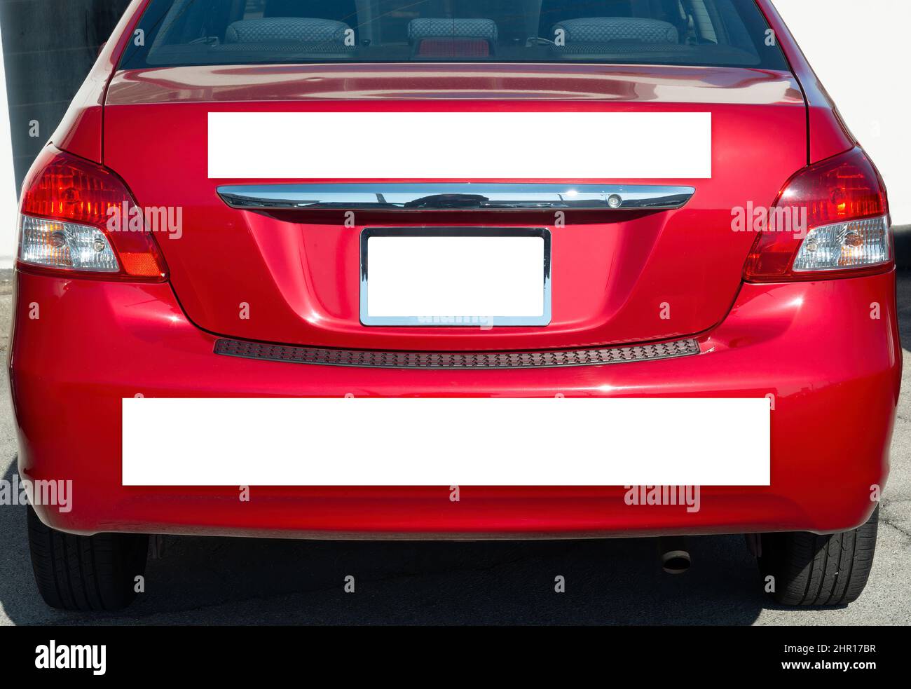 Primer plano horizontal del extremo trasero de un pequeño coche rojo genérico con tres señales en blanco. Foto de stock