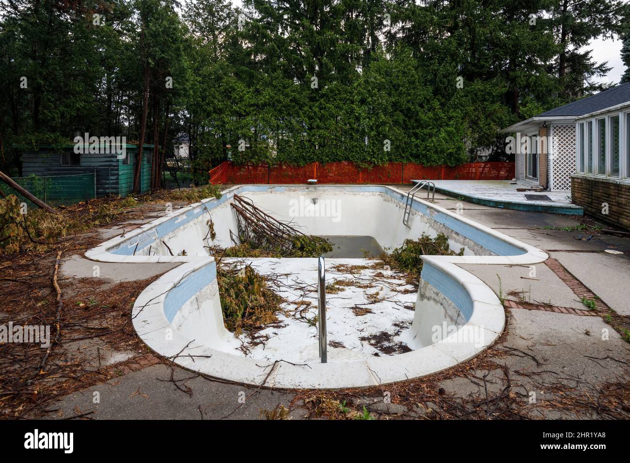 Una piscina exterior sucia con árboles en su interior. Esta casa ha sido demolida. Foto de stock