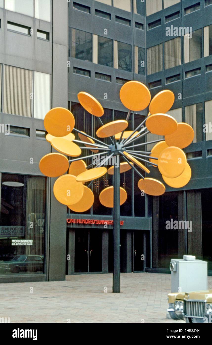 Una vista de 1980 de 'Helion', más informalmente conocido como 'el lollipop', frente a 100 Summer Street, Boston, Massachusetts, EE.UU. El móvil fue creado por el artista de Gloucester Robert Amory en 1975. Esta escultura es parte de la serie 'windflowers' de Amory y lleva el nombre del dios griego Helios. Cuando el viento sopla en los discos naranjas, el cojinete de bolas gira y los discos giran. Cuando se vendió el edificio, sus nuevos propietarios pidieron que se trasladara el lollipop, que ahora reside en Madison Park Village. Esta imagen proviene de una antigua transparencia de color amateur, una fotografía vintage de 1980s. Foto de stock