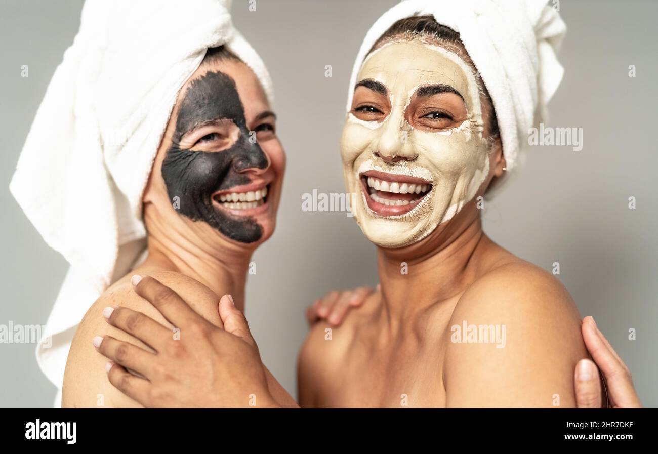 Mujeres felices con máscara facial teniendo cuidado de la piel día de spa - personas auto cuidado concepto de estilo de vida Foto de stock