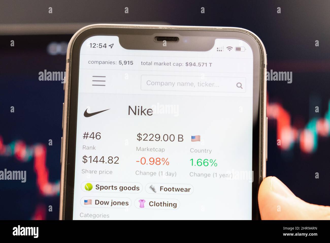 El precio de las acciones de Nike en la pantalla del teléfono móvil en  manos de los hombres con los cambios en los gráficos del mercado de valores  en segundo plano, febrero