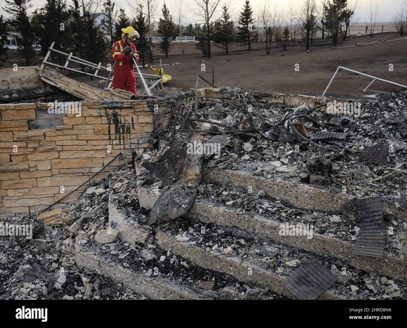 Un caza de incendios se atiene a un punto caliente mientras supervisa los restos de una casa que fue destruida por incendios de pasto cerca de Airdrie, Alta., miércoles, 18 de octubre de 2017. LA PRENSA CANADIENSE/Jeff McIntosh Foto de stock