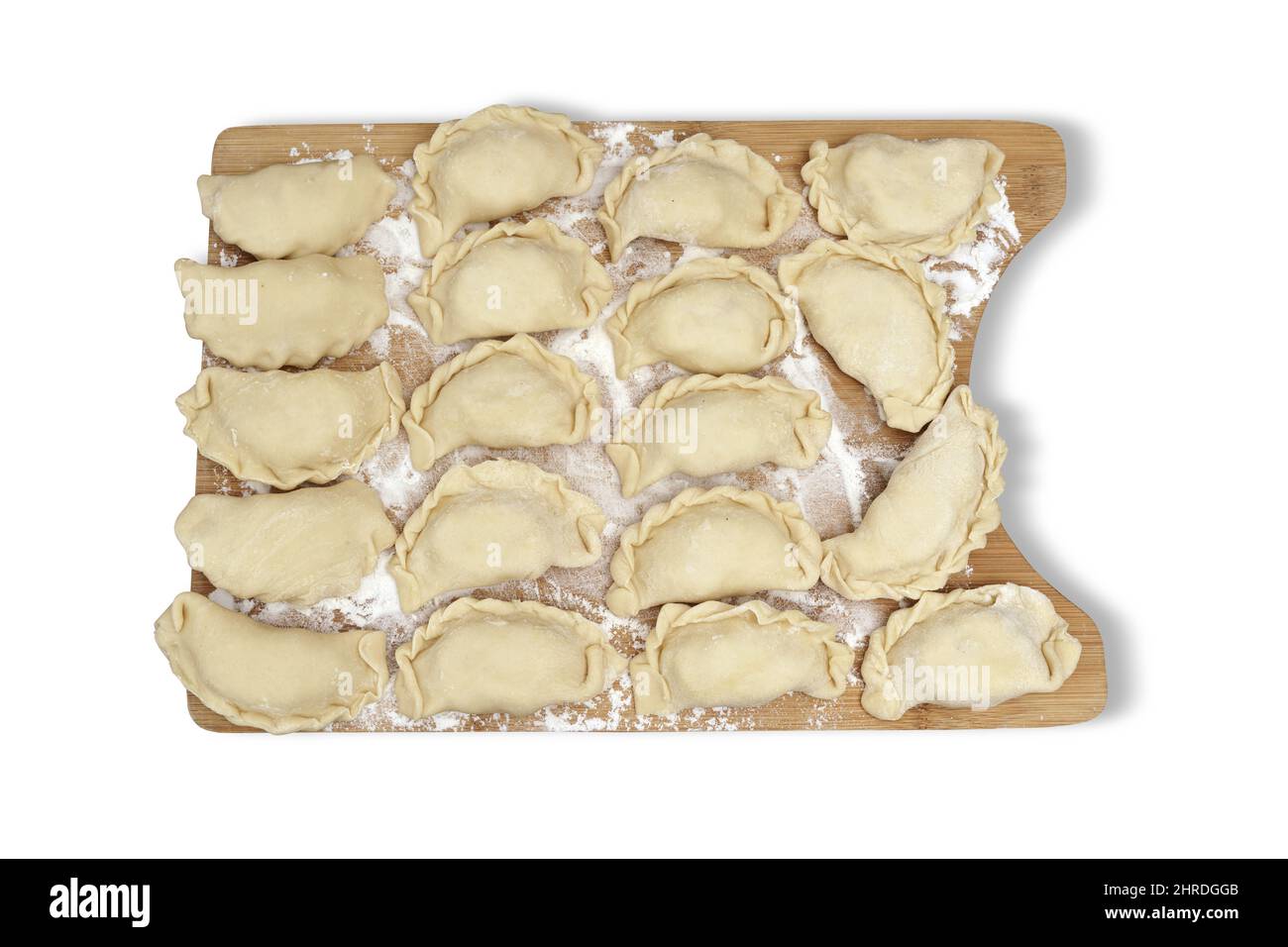 Buñuelos crudos rellenos de queso blanco tumbados sobre una tabla de madera en un fondo blanco aislado. Plato tradicional polaco. Foto de stock