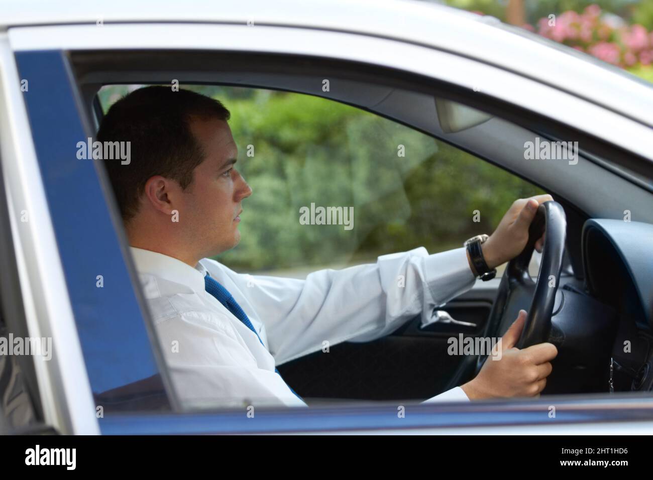 Los desplazamientos diarios. Perfil de un hombre de negocios que conduce su coche al trabajo. Foto de stock