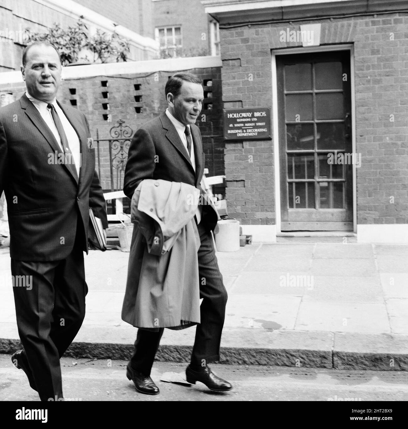 Frank Sinatra, fotografiado con Bradford Dexter, su colega de negocios y ex actor, al salir de su apartamento, a través de la entrada del comerciante, en Grosvenor Square, Londres, 1st de agosto de 1966. Foto de stock