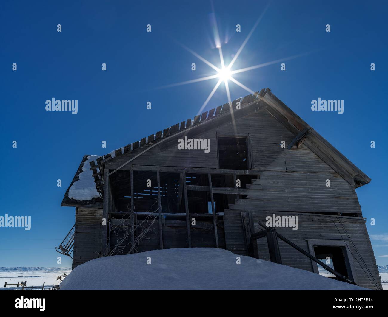 Ángulo inusual en una casa abandonada con un montón de nieve y estrella del sol Foto de stock
