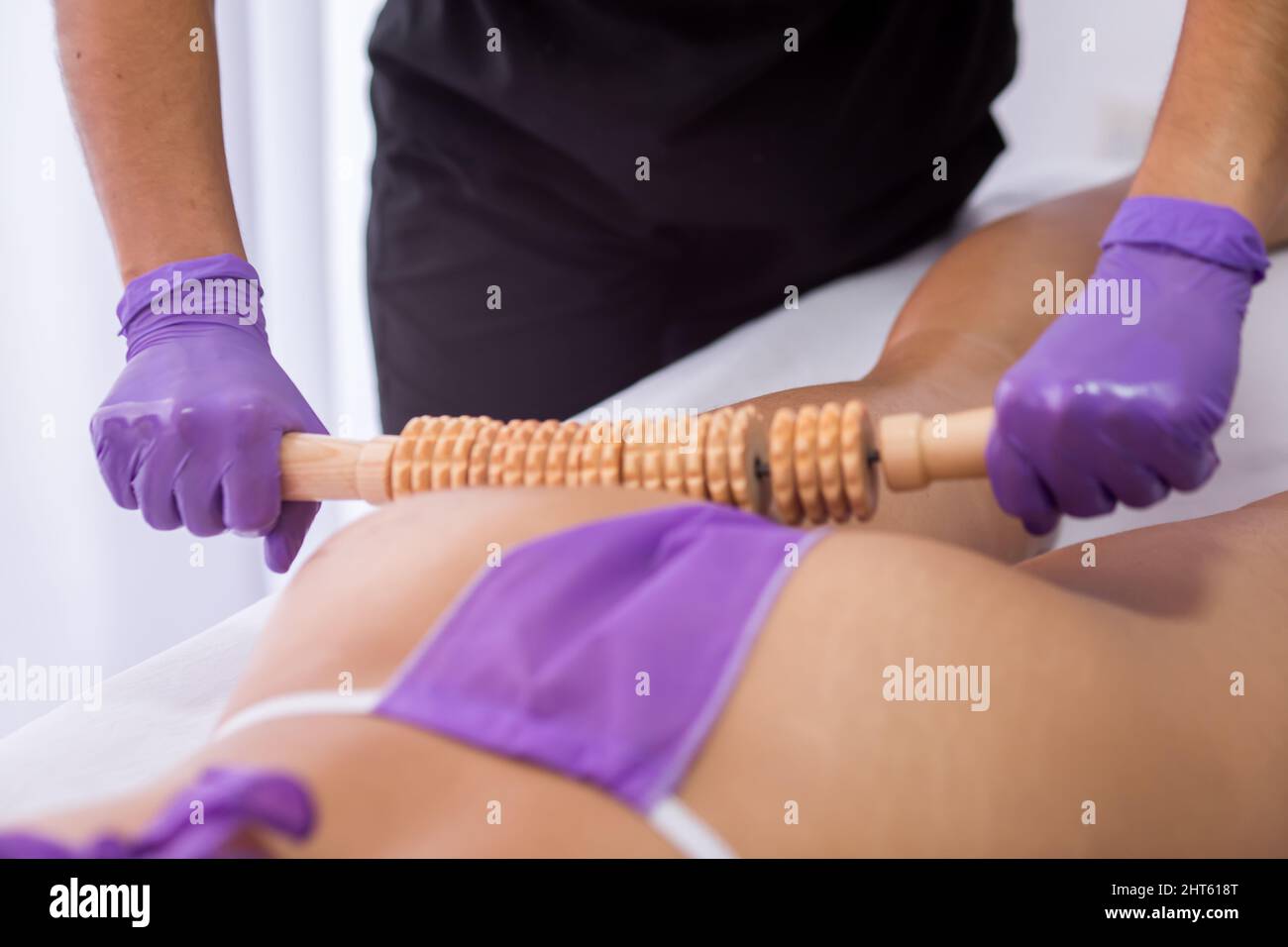 Mujer hispana haciendo masajes a otra mujer en un bikini violeta usando un  masajeador de madera Fotografía de stock - Alamy