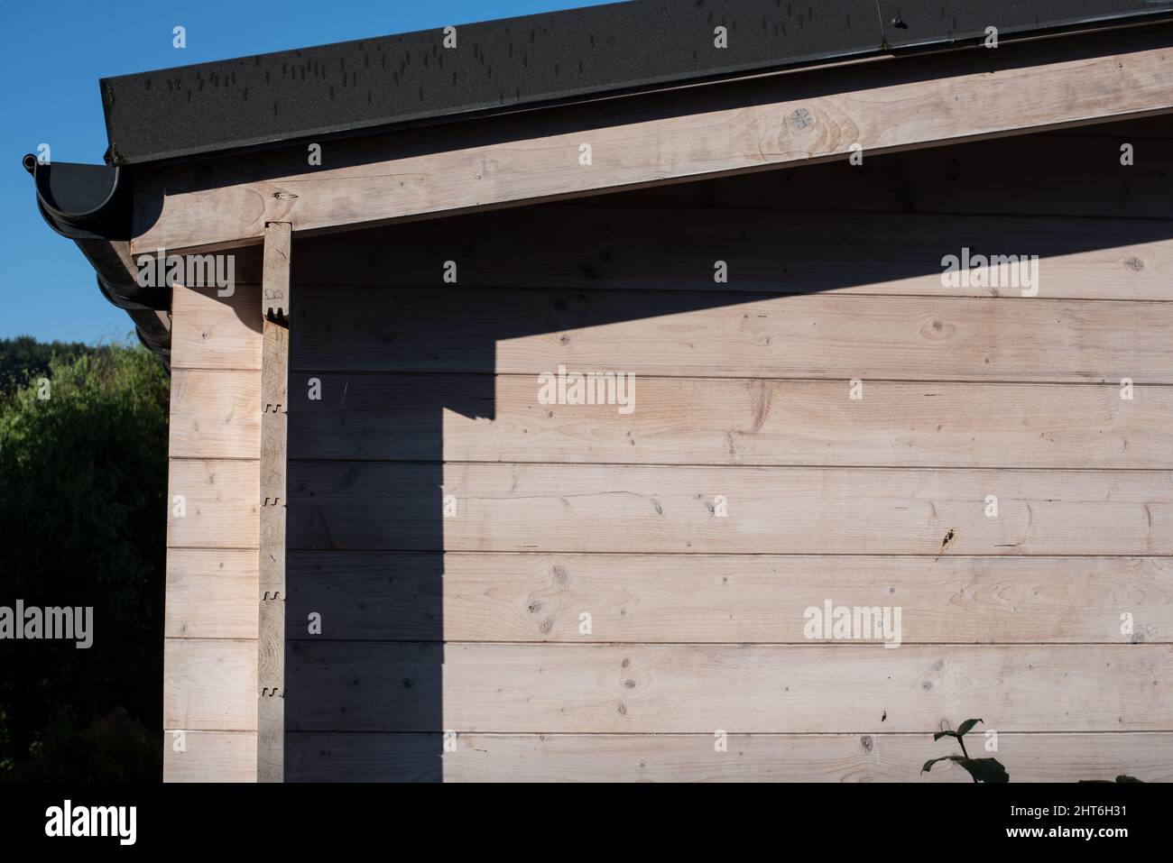 los tablones de madera de una moderna cabaña de jardín con una canaleta de techo Foto de stock