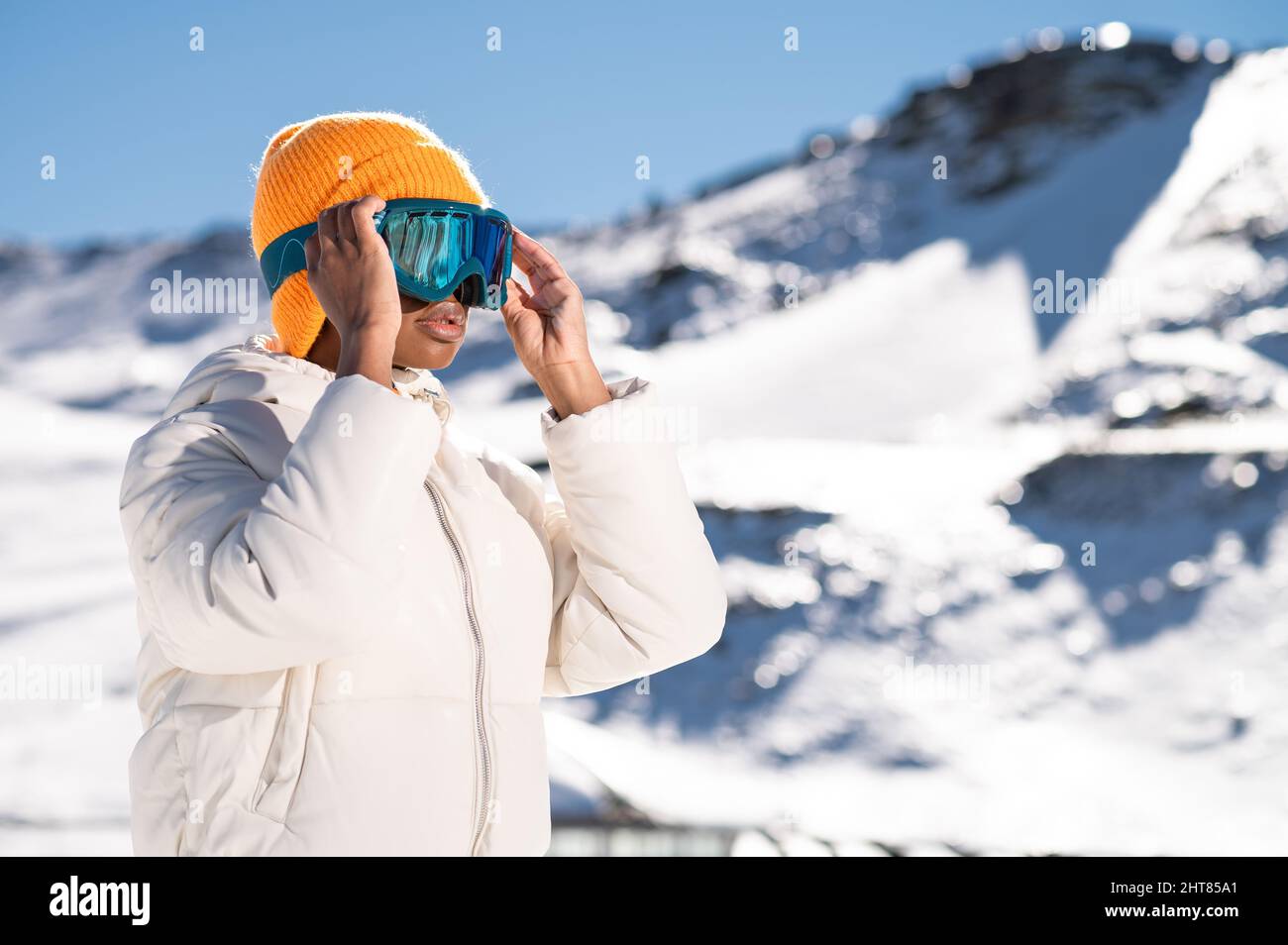Una mujer afroamericana con gafas de nieve en una montaña nevada