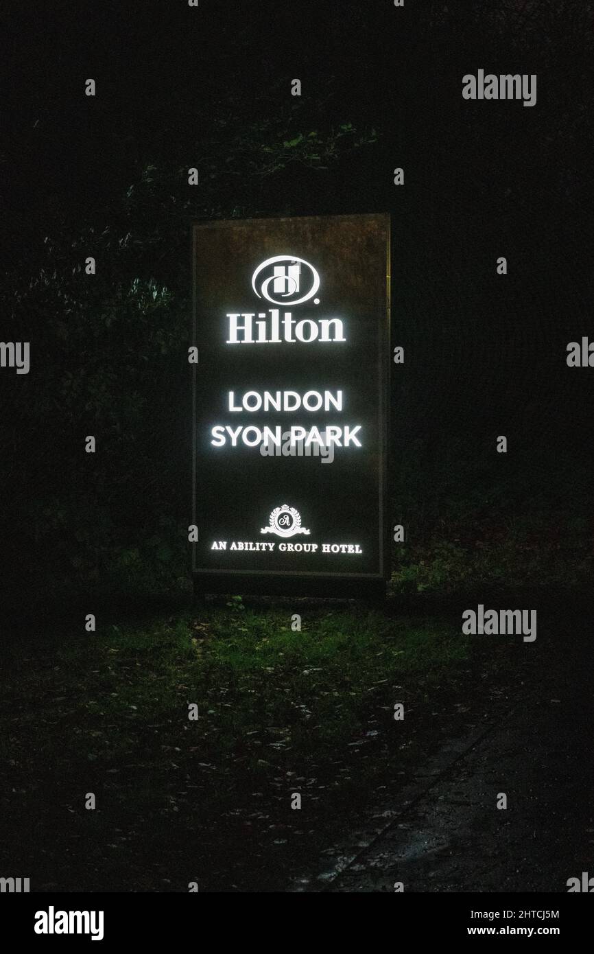 Señal para el hotel Hilton en Syon Park iluminado por la noche Foto de stock