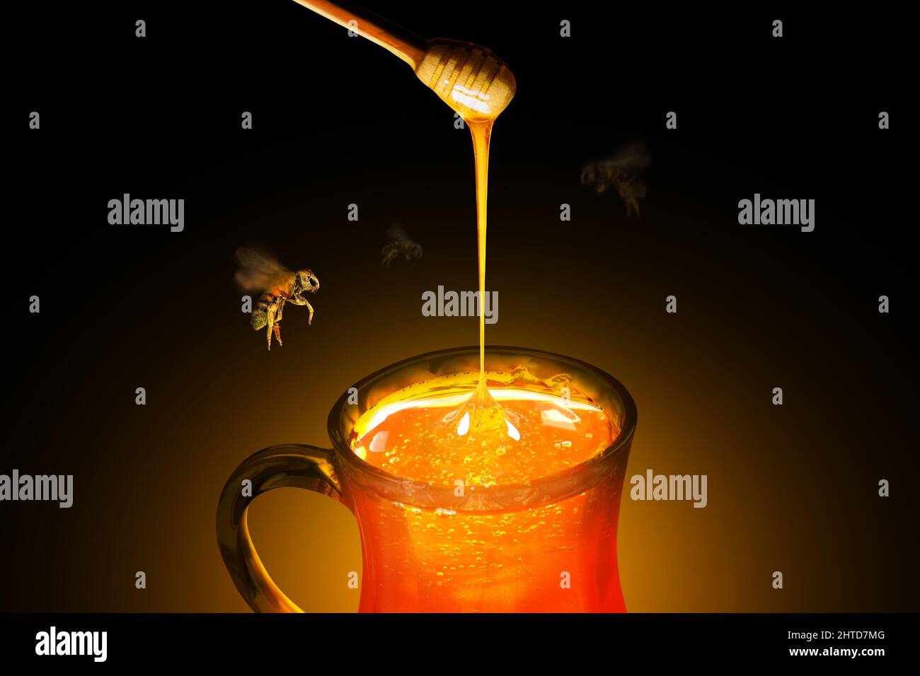 Taza de cristal llena de miel pura y un penetrador con abejas volando alrededor Foto de stock