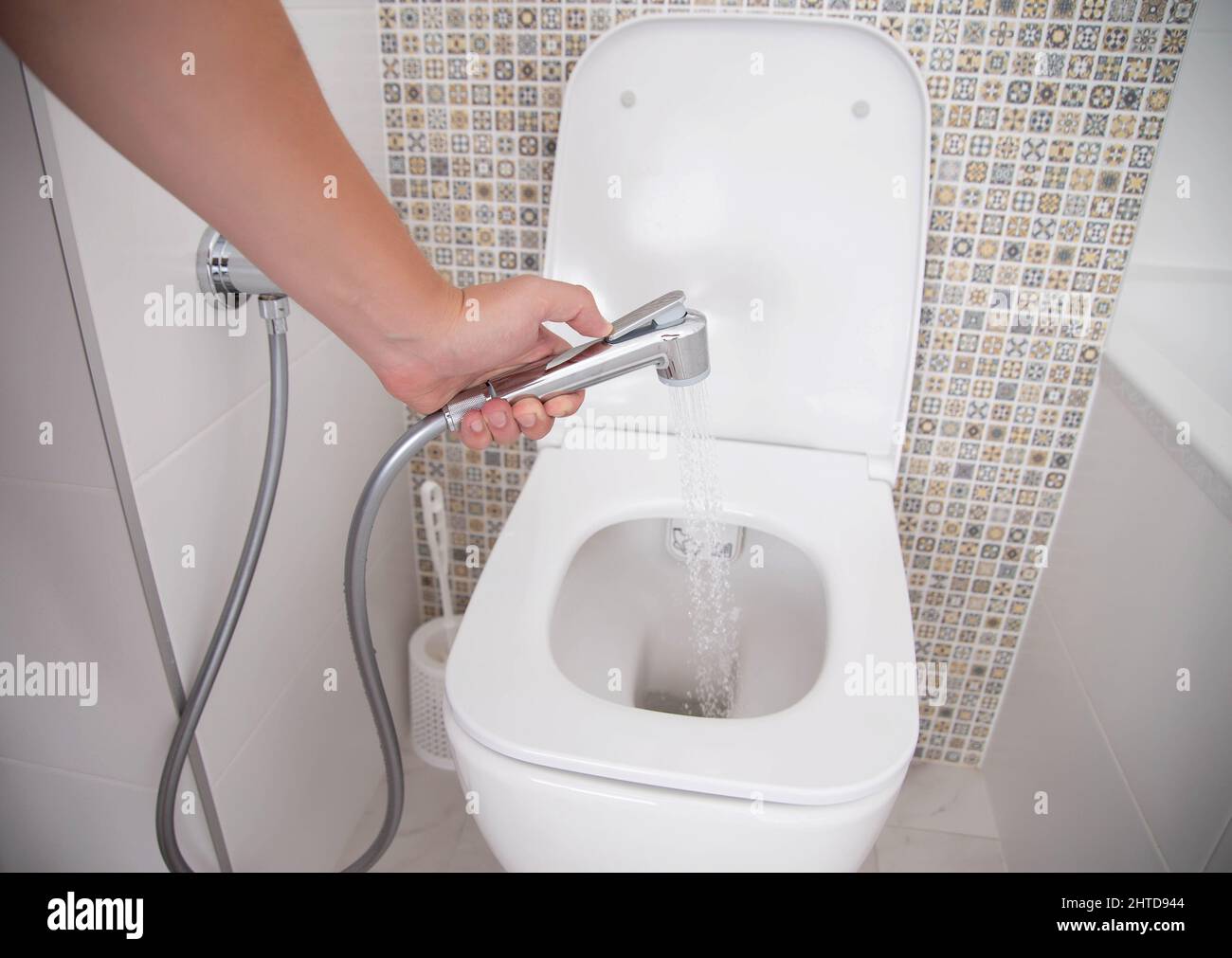 Baño con ducha higiénica para lavar los genitales externos. Una mano  sosteniendo una ducha higiénica Fotografía de stock - Alamy