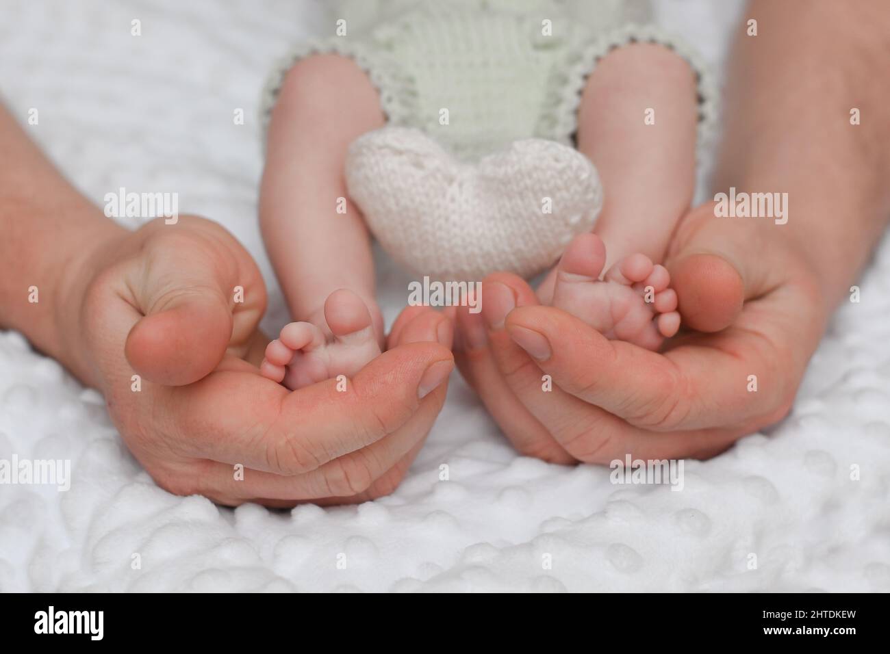 las piernas de un bebé recién nacido en las manos de un padre. el concepto de amor paterno y una familia feliz. Foto de stock