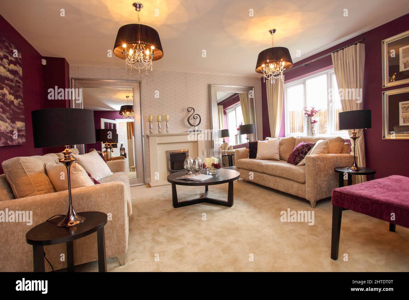Salón moderno en casa de nueva construcción, alfombra beige y sofá cama, púrpura, rojo oscuro, paredes de borgoña, mesa de café. Foto de stock