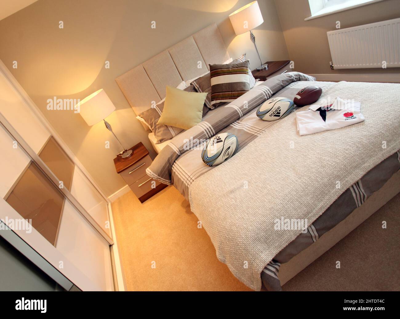Habitación moderna para chicos en casa nueva, tema de rugby, colcha, esquema de color beige neutro, alto acolchado con detalle cabecero, pelotas de rugby, dormitorio para chicos, Foto de stock