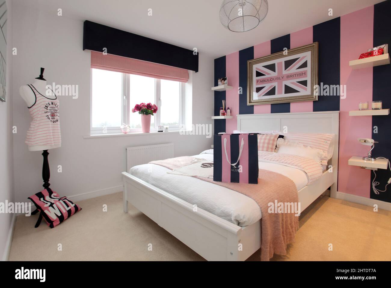 Dormitorio moderno en casa de nueva construcción, colcha, esquema de colores rosa beige, tema Jack Wills Foto de stock