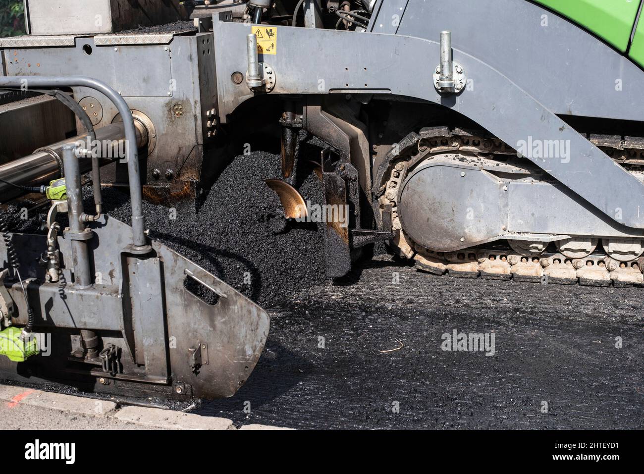 primer plano de una máquina asfaltada que extiende asfalto sobre una calle en reparación Foto de stock