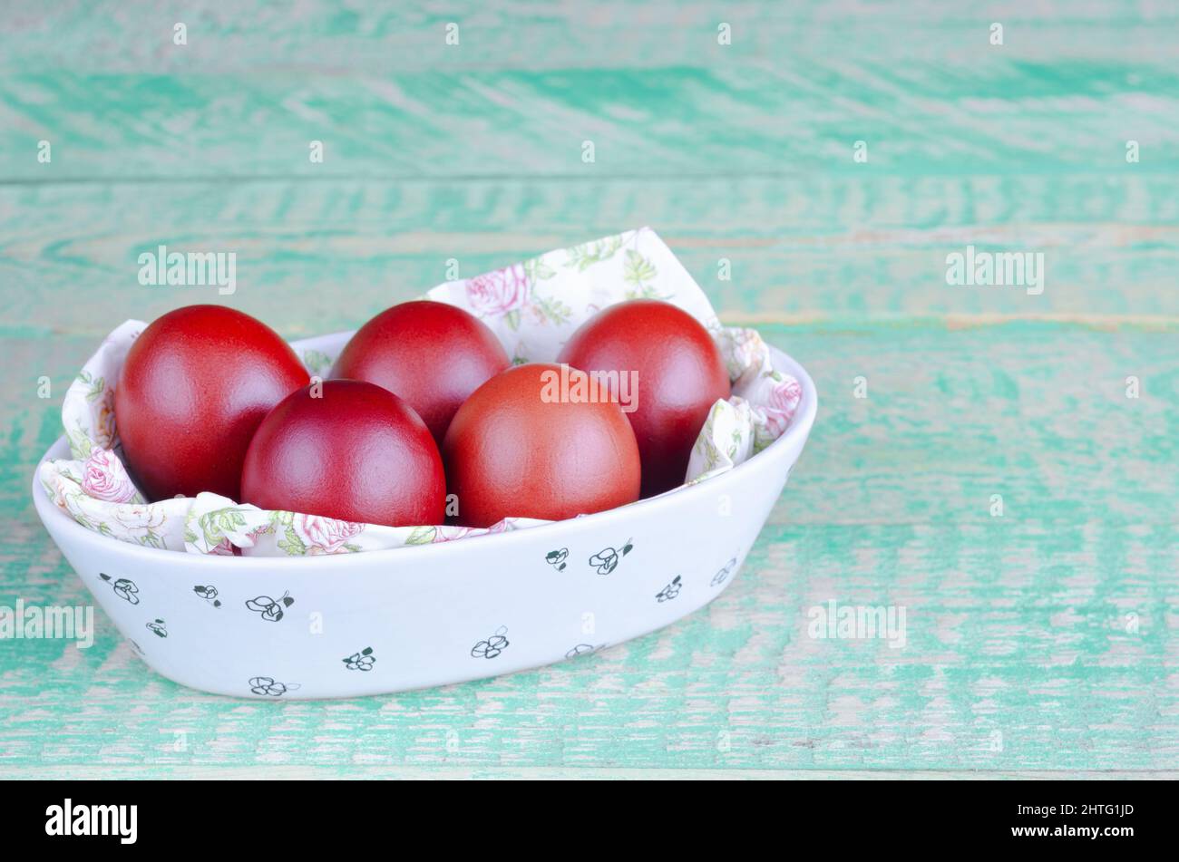 Huevos de Pascua rojos en un tazón, sobre un viejo fondo de madera. Enfoque selectivo Foto de stock