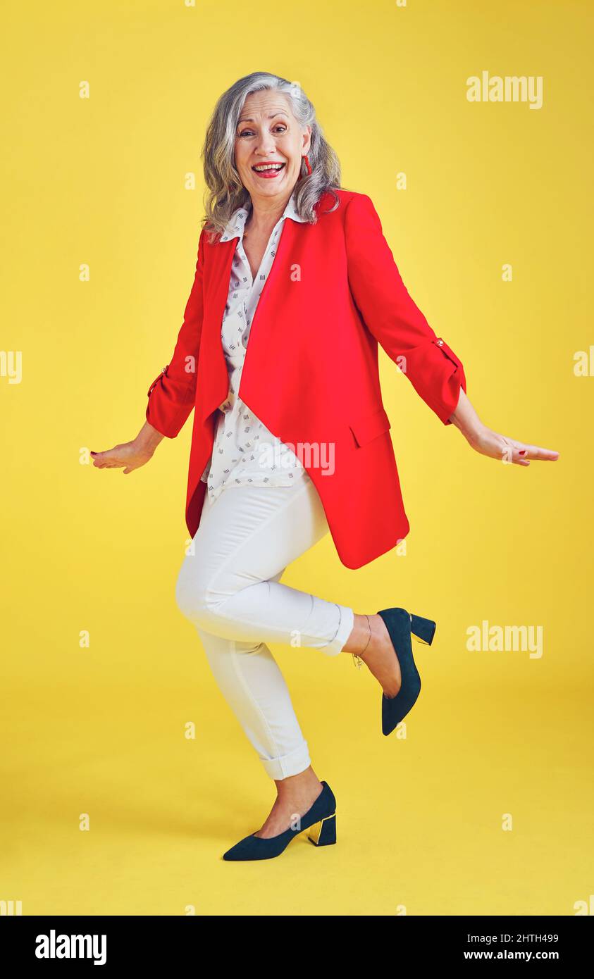 Su estilo y sentido de la moda dicen mucho sobre usted. Fotografía completa de una mujer mayor moderna y elegante posando en el estudio sobre un fondo amarillo. Foto de stock