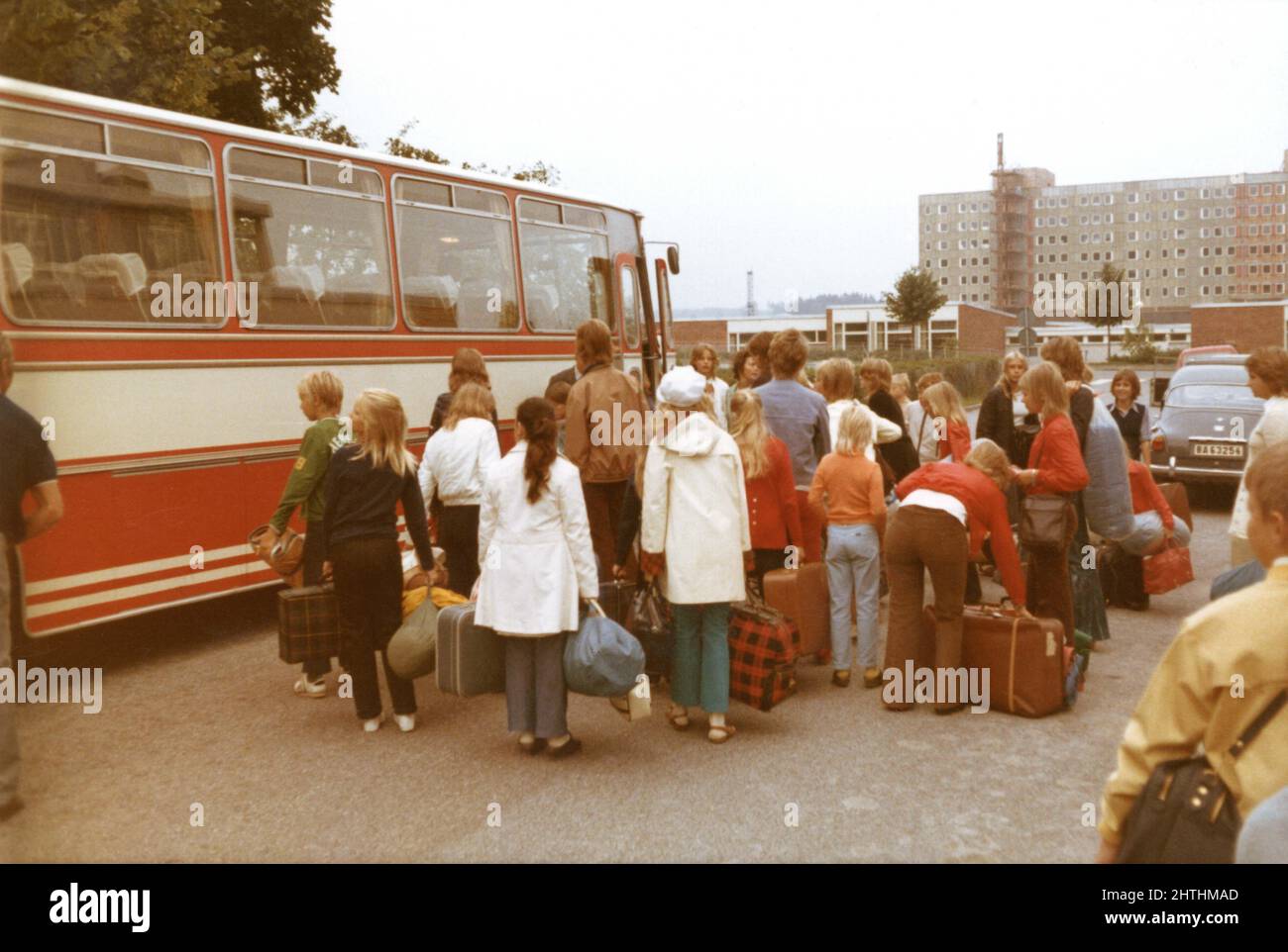 Fotografía de los años 70 de niños haciendo cola con equipaje para el viaje en autobús escolar, Suecia Foto de stock