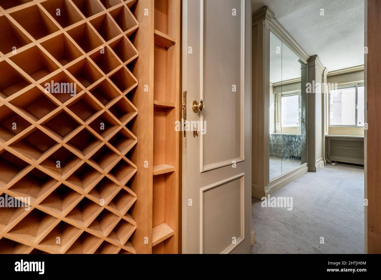 Botellero de madera que cubre una pared en una habitación al lado de una  sala de estar con murales de madera y espejo en las paredes Fotografía de  stock - Alamy