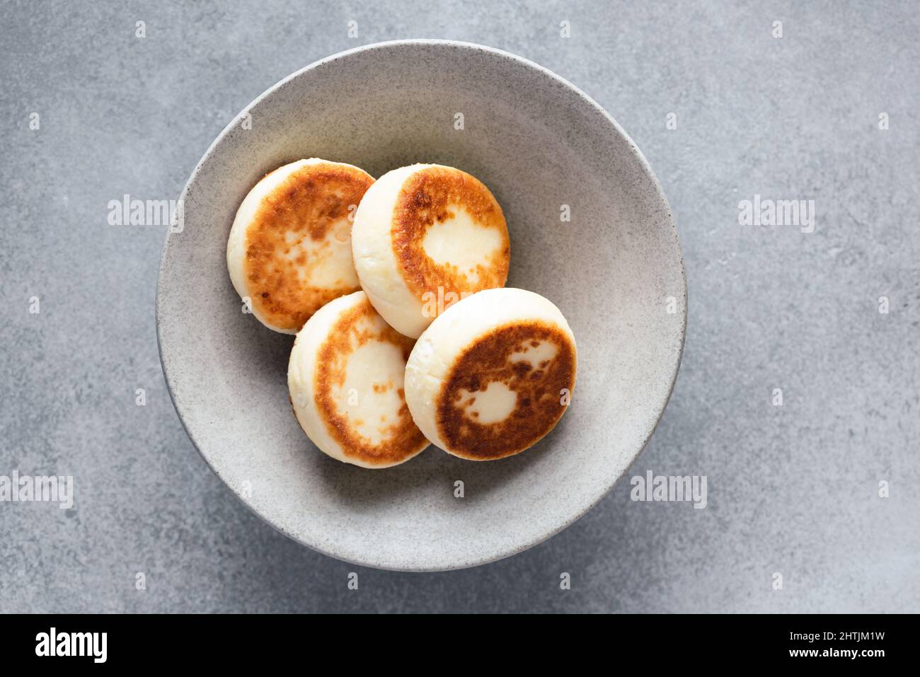 Syrniki, fritters de queso cottage sobre placa cerámica gris, vista superior. Comida de desayuno Foto de stock