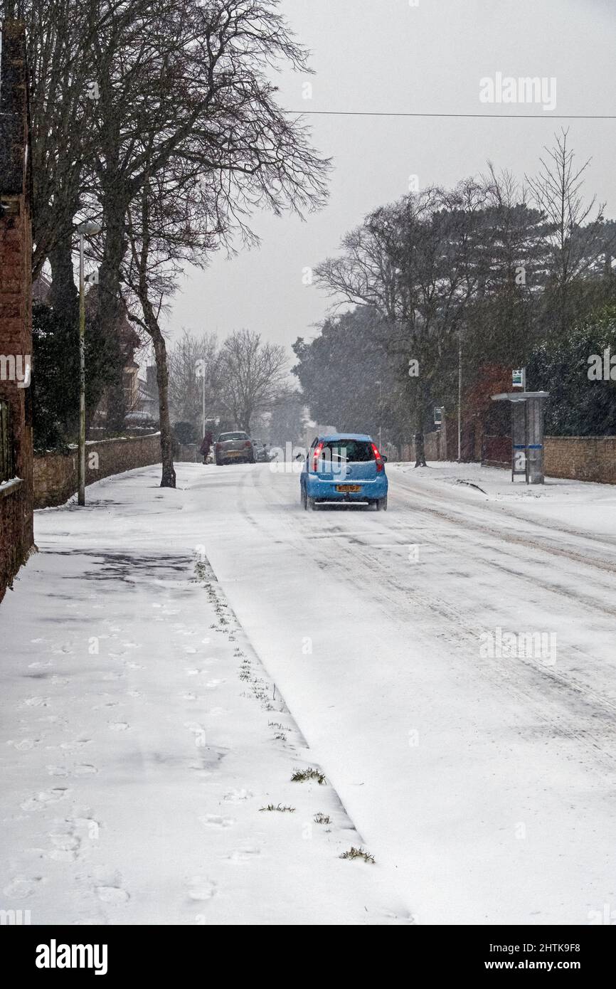 El 1 de marzo de 2018, durante la tormenta llamada “La Bestia del Este”, un coche pasa por la caída de nieve en una carretera desierta en Weston-super-Mare (Reino Unido) Foto de stock