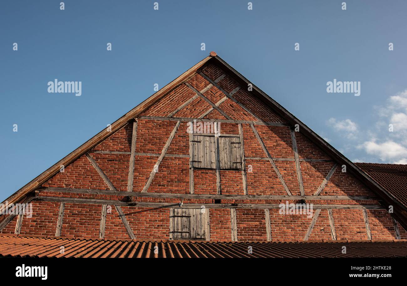 un hastial de entramado de madera en un granero construido de ladrillos rojos en la campiña alemana Foto de stock