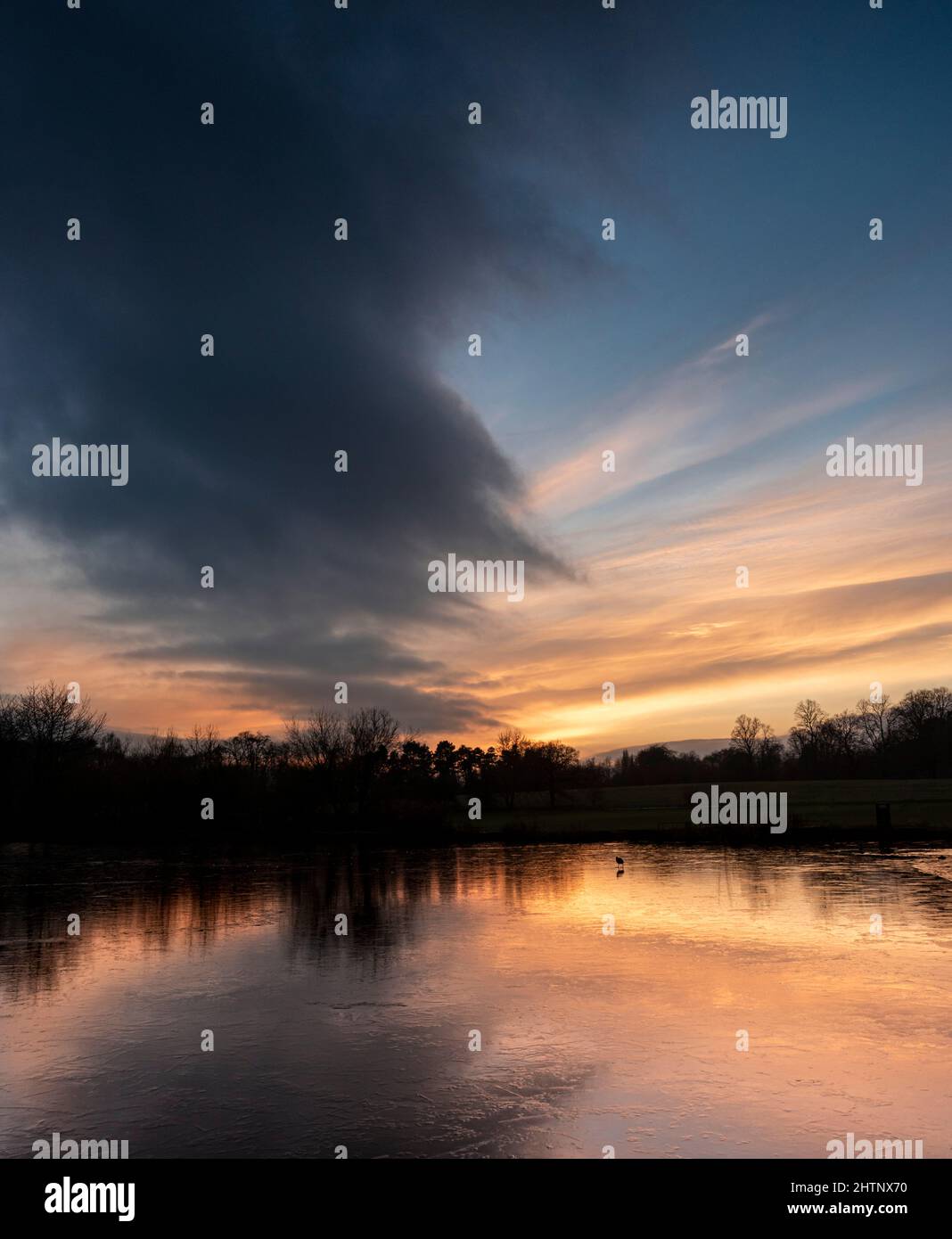 Puesta de sol en el cielo de colores sobre un lago congelado. Bulwell Hall Park Nottingham Inglaterra Reino Unido Foto de stock