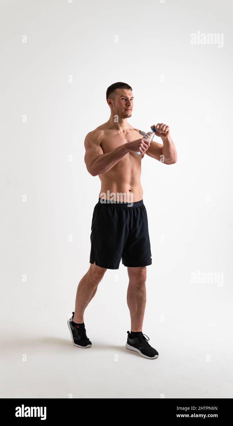 El sexo masculino de la bebida-agua fitness se bombea con una toalla sobre un fondo blanco aislado cuerpo muscular fitness, agua gimnasio persona adulta, fondo cardio. Toalla Foto de stock